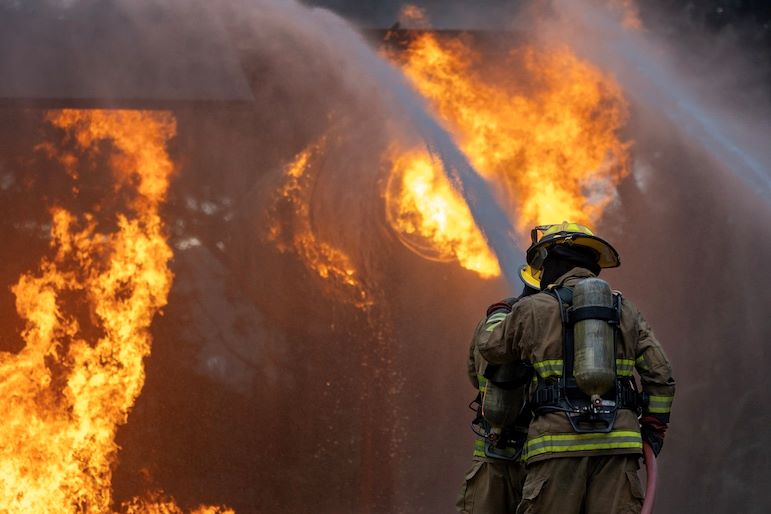 firefighter spraying water on house fire