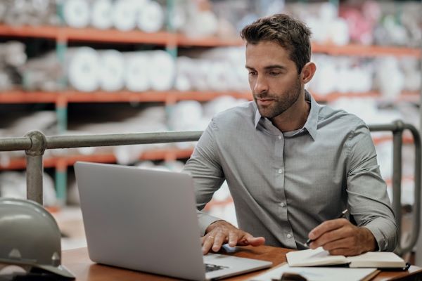 supply chain manager working on laptop in warehouse